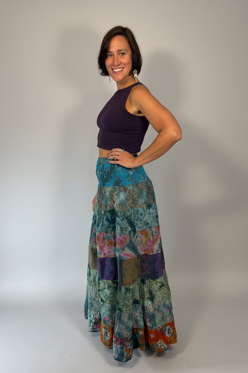 Model wearing the Savvy Munk Prism Flow Tiered Boho Maxi Skirt, showcasing the flowing silhouette, vibrant handcrafted patterns, and artisan cotton quality in a studio setting.