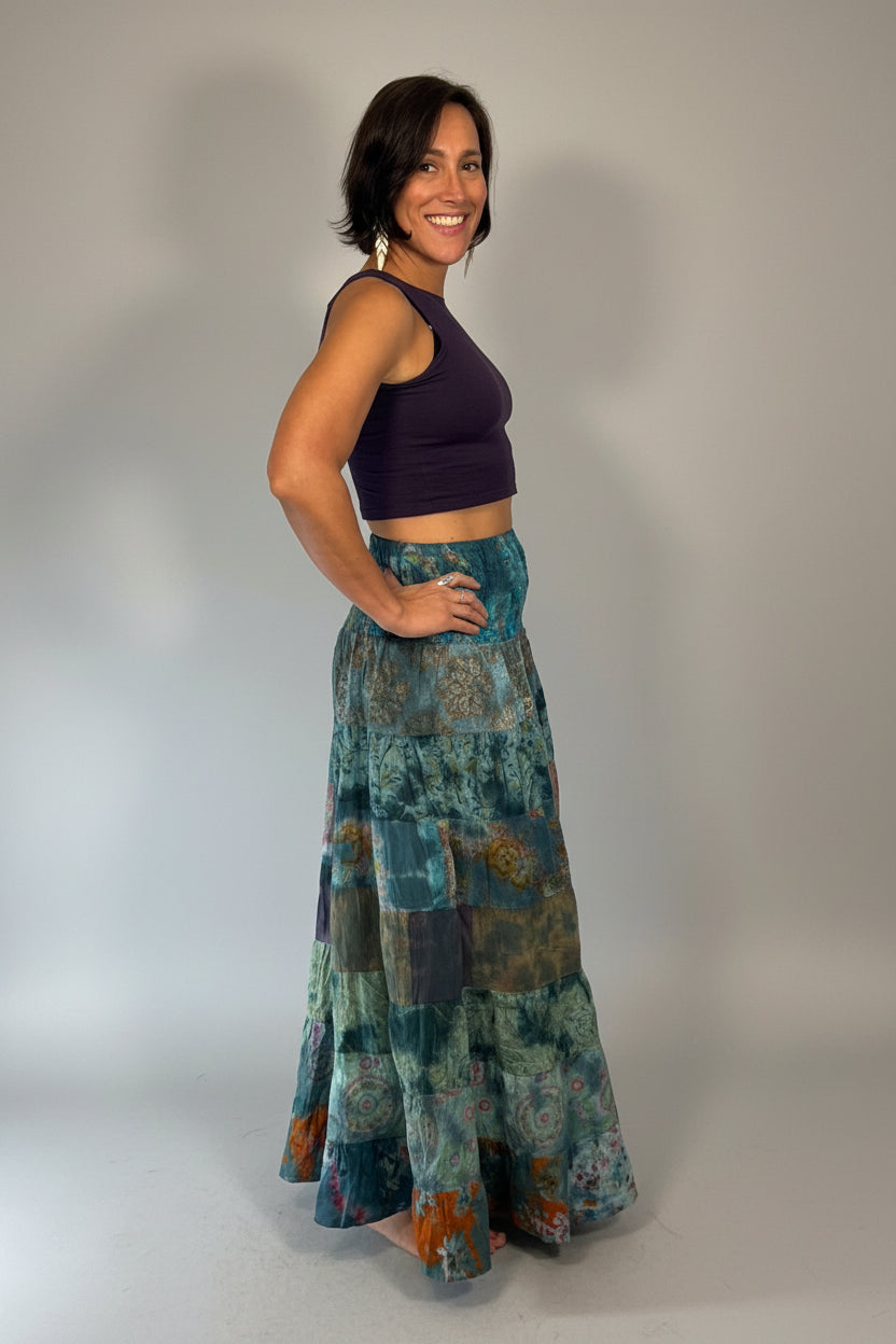 Model wearing the Savvy Munk Prism Flow Tiered Boho Maxi Skirt, showcasing the flowing silhouette, vibrant handcrafted patterns, and artisan cotton quality in a studio setting.