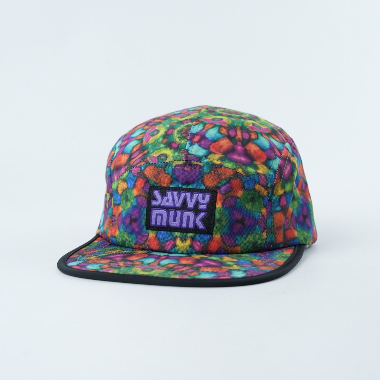 Savvy Munk Grass Water 5-Panel Hat displayed flat, highlighting the vibrant psychedelic print and embroidered brand logo patch.