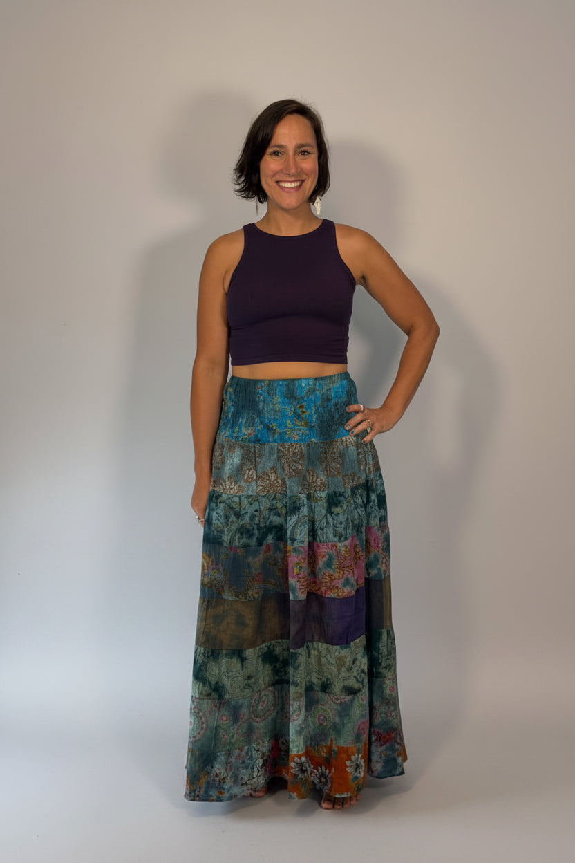 Model wearing the Savvy Munk Prism Flow Tiered Boho Maxi Skirt, showcasing the flowing silhouette, vibrant handcrafted patterns, and artisan cotton quality in a studio setting.
