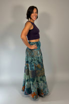 Model wearing the Savvy Munk Prism Flow Tiered Boho Maxi Skirt, showcasing the flowing silhouette, vibrant handcrafted patterns, and artisan cotton quality in a studio setting.