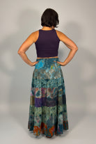 Model wearing the Savvy Munk Prism Flow Tiered Boho Maxi Skirt, showcasing the flowing silhouette, vibrant handcrafted patterns, and artisan cotton quality in a studio setting.
