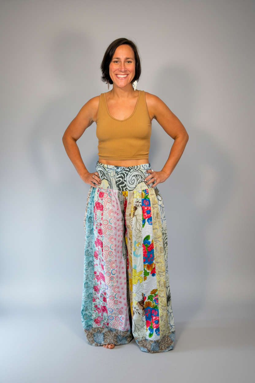 Model wearing the Savvy Munk Meadows of Nepal Palazzo Pants with colorful floral patchwork patterns, styled with a tan crop top against a clean studio background