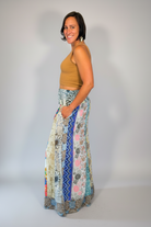 Model wearing the Savvy Munk Meadows of Nepal Palazzo Pants with colorful floral patchwork patterns, styled with a tan crop top against a clean studio background